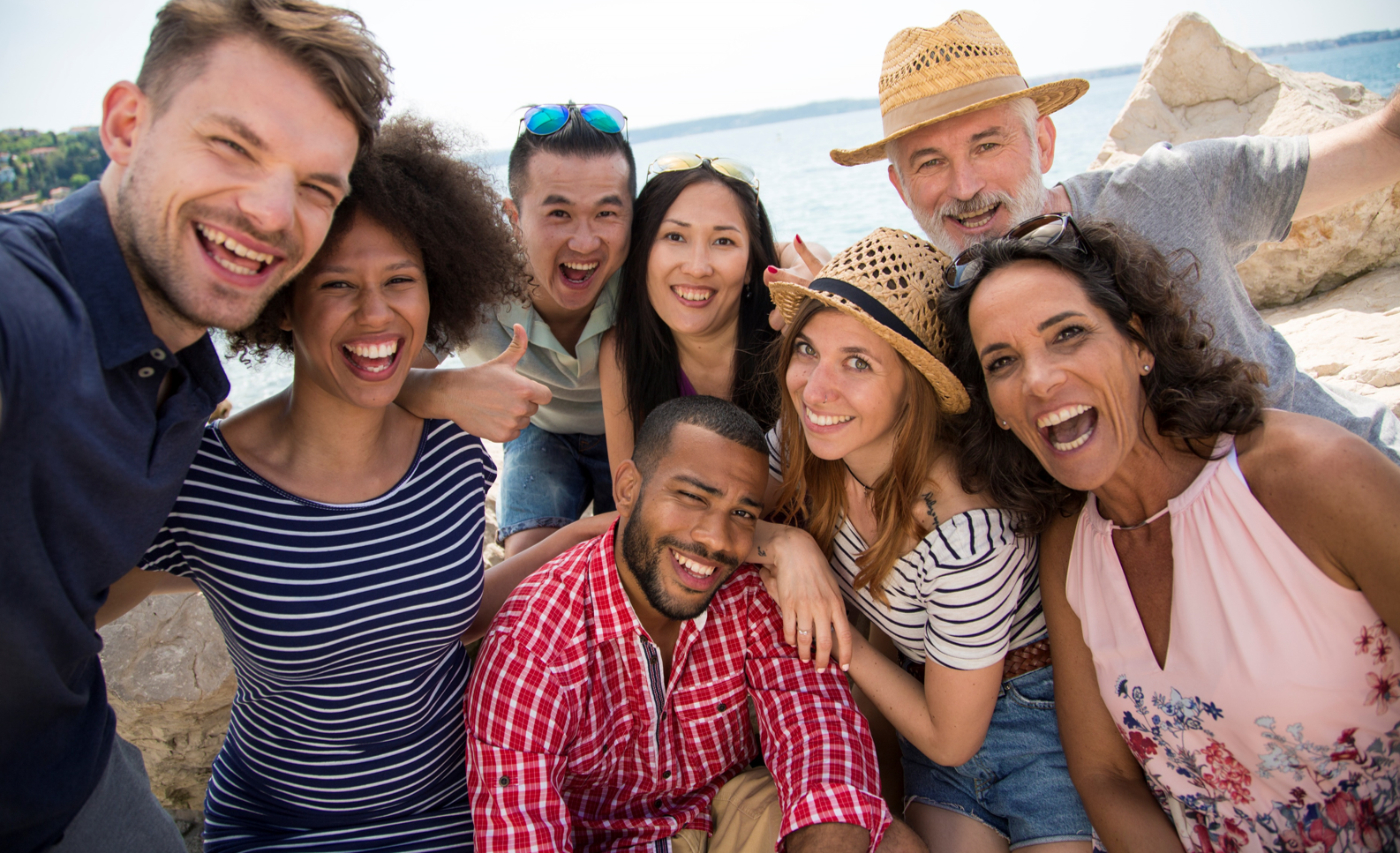 close-up view of people with grin on their face posing for a selfie by a coast
