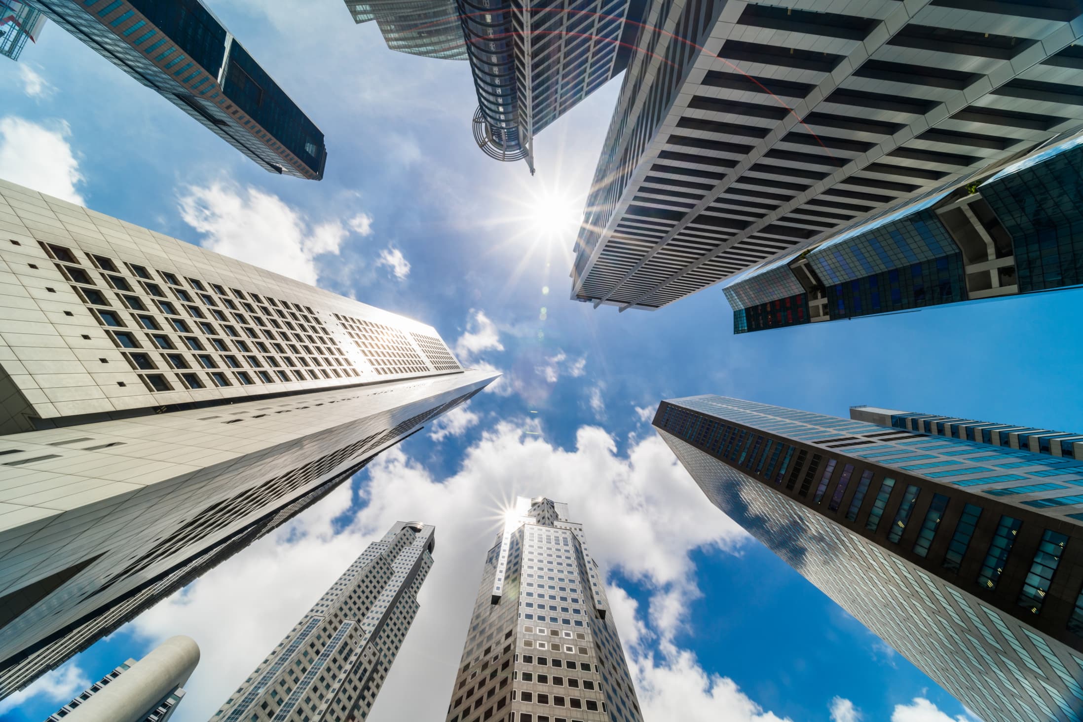 multiple skyscrappers in a circle merging in to a point when viewed from the center towards the white-cloudy sky